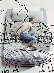 Image showing Top view photo of young man sleeping in a big white bed and his dreams