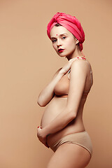 Image showing Young beautiful pregnant woman posing on brown background