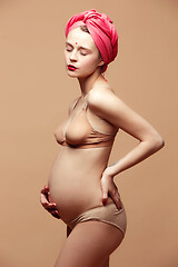 Image showing Young beautiful pregnant woman posing on brown background