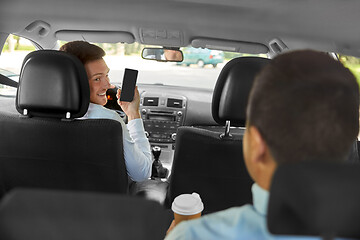 Image showing car driver showing smartphone to male passenger