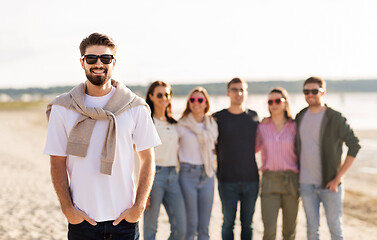 Image showing happy man with friends on beach in summer