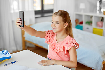 Image showing happy girl with smartphone taking selfie at home