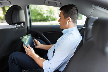 Image showing passenger with earphones and tablet pc in taxi car