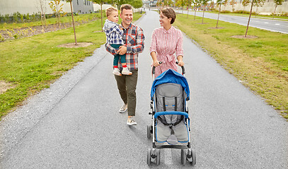 Image showing family with baby and stroller walking along city