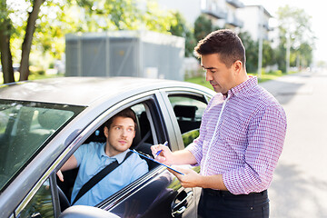 Image showing car driving instructor with clipboard and driver