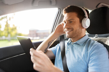 Image showing passenger in headphones with tablet pc in taxi car