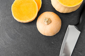 Image showing cut pumpkin and kitchen knife on stone background