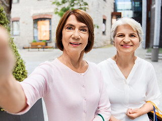 Image showing old women with shopping bags taking selfie in city