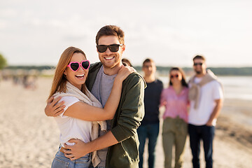 Image showing happy friends walking along summer beach