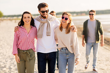 Image showing happy friends walking along summer beach