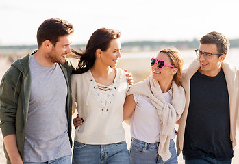 Image showing happy friends walking along summer beach