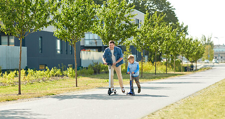 Image showing father and little son riding scooters in city