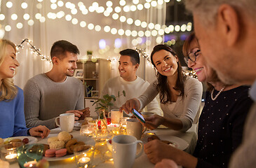 Image showing happy family with smartphone at tea party at home