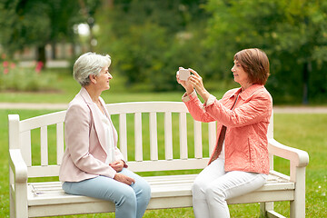 Image showing senior woman photographing her friend at park