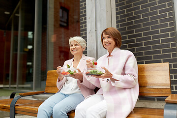 Image showing senior women eating takeaway food on city street