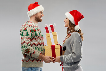 Image showing happy couple in christmas sweaters with gifts