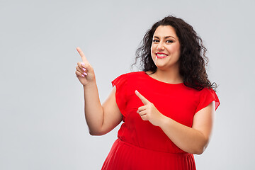 Image showing happy woman in red pointing fingers at something