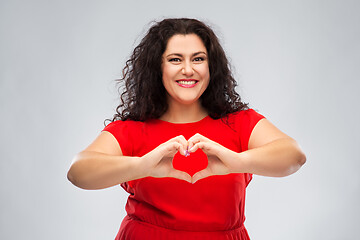 Image showing happy woman in red dress showing hand heart