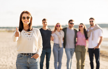 Image showing woman with friends on beach showing thumbs up