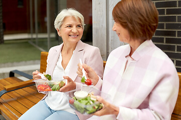 Image showing senior women eating takeaway food on city street