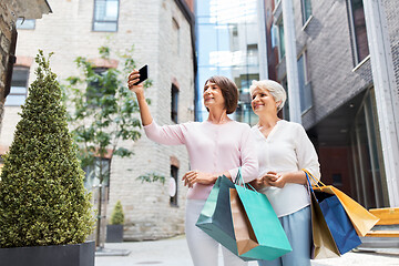 Image showing old women with shopping bags taking selfie in city