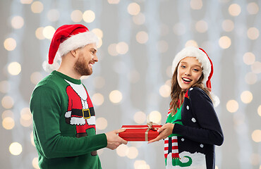 Image showing happy couple in christmas sweaters with gift box