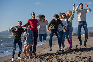 Image showing young friends jumping together at autumn beach