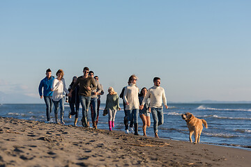 Image showing Group of friends running on beach during autumn day