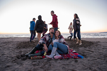 Image showing Couple enjoying with friends at sunset on the beach