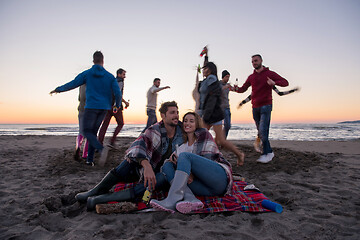 Image showing Couple enjoying with friends at sunset on the beach