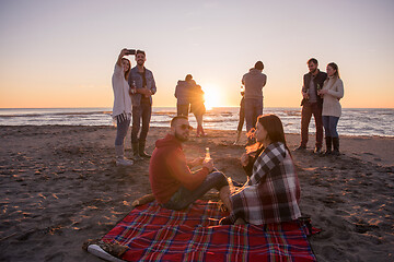 Image showing Couple enjoying with friends at sunset on the beach