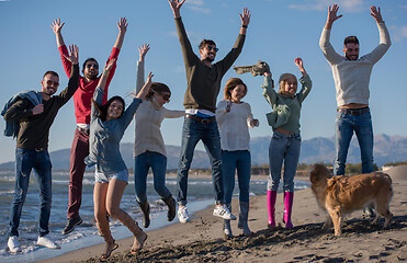 Image showing young friends jumping together at autumn beach