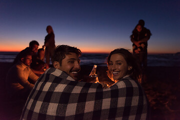 Image showing Couple enjoying with friends at sunset on the beach