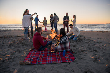 Image showing Couple enjoying with friends at sunset on the beach