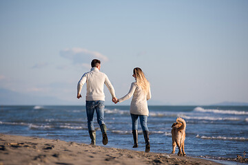 Image showing couple with dog having fun on beach on autmun day