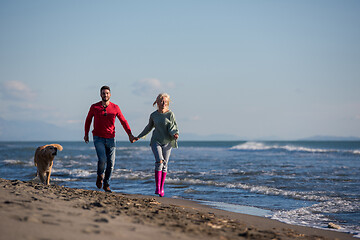 Image showing couple with dog having fun on beach on autmun day