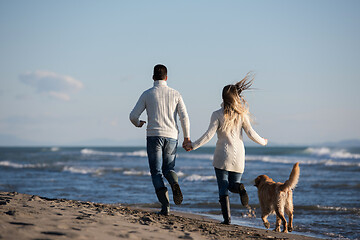 Image showing couple with dog having fun on beach on autmun day