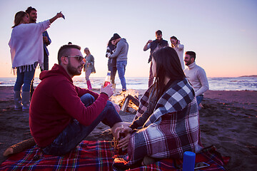 Image showing Couple enjoying with friends at sunset on the beach