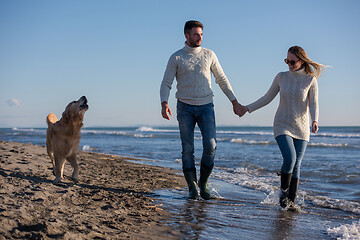 Image showing couple with dog having fun on beach on autmun day