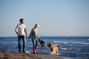 Image showing couple with dog having fun on beach on autmun day