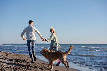 Image showing couple with dog having fun on beach on autmun day