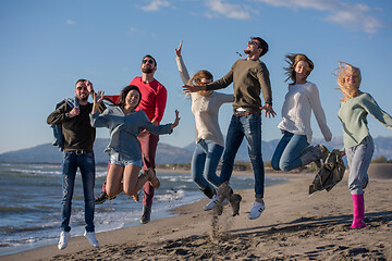 Image showing young friends jumping together at autumn beach