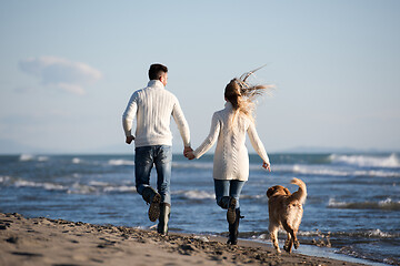 Image showing couple with dog having fun on beach on autmun day