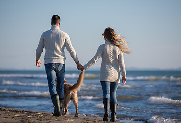 Image showing couple with dog having fun on beach on autmun day