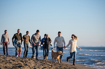 Image showing Group of friends running on beach during autumn day