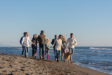 Image showing Group of friends running on beach during autumn day