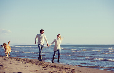 Image showing couple with dog having fun on beach on autmun day