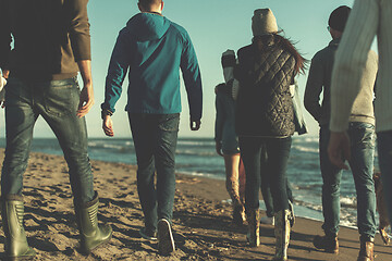 Image showing Group of friends running on beach during autumn day