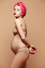 Image showing Young beautiful pregnant woman posing on brown background