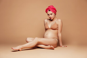 Image showing Young beautiful pregnant woman posing on brown background